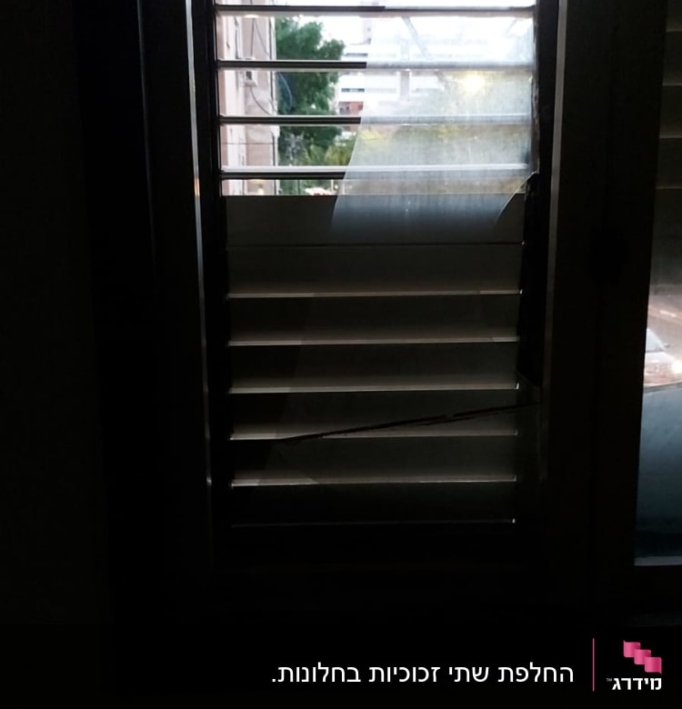 חלון עם זכוכית שבורה ותריסים פתוחים